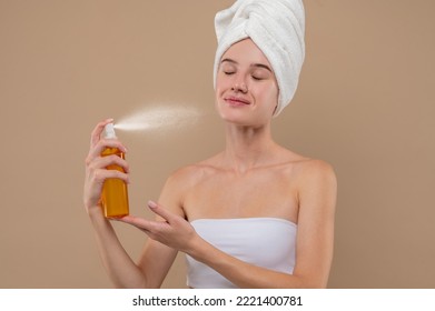 Young girl spraying hydrating mist on her face