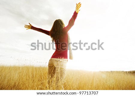 Young girl spreading hands with joy and inspiration facing the sun