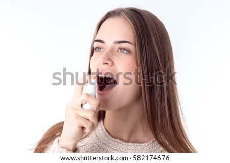 Young Girl Squirting Sore Throat Spray Is Isolated On A White Background Young Girl Squirting Sore Throat Spray Is Isolated On A White Background