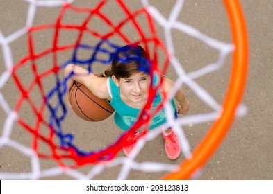 Young Girl Standing With Basketball Under Hoop