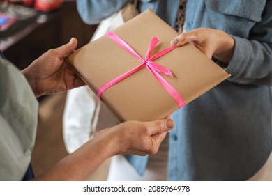 Young girl standing in front her mature tutor and giving present with pink ribbon to her - Shutterstock ID 2085964978