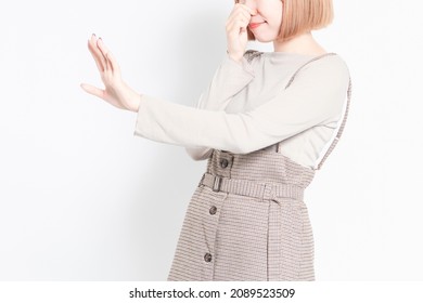 A Young Girl Standing In Front Of A White Background And Posing With A Foul Odor And Pinching Her Nose