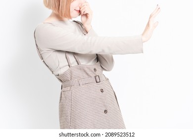 A Young Girl Standing In Front Of A White Background And Posing With A Foul Odor And Pinching Her Nose