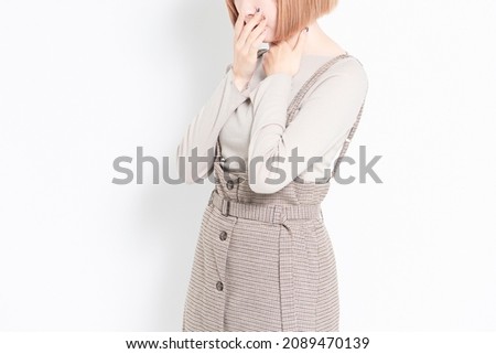 Young girl standing in front of a white background and making a sore throat pose