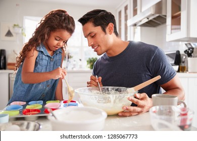 Young Girl Standing At The Kitchen Table Making Cakes With Her Father, Filling Cake Forms, Close Up