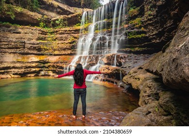 young girl standing near waterfall flowing streams falling from mountain at morning from low angle image is taken at wei sawdong falls cherrapunji sohra district meghalaya india.