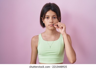 Young Girl Standing Over Pink Background Mouth And Lips Shut As Zip With Fingers. Secret And Silent, Taboo Talking 