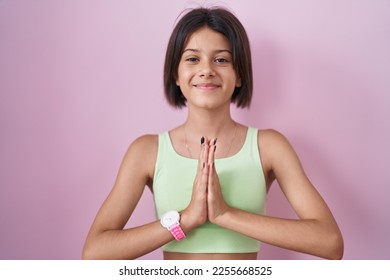 Young girl standing over pink background praying with hands together asking for forgiveness smiling confident.  - Shutterstock ID 2255668525
