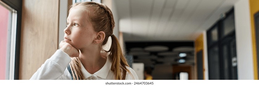 A young girl stands by a window, gazing out into the world with a thoughtful expression, captivated by the unseen. - Powered by Shutterstock