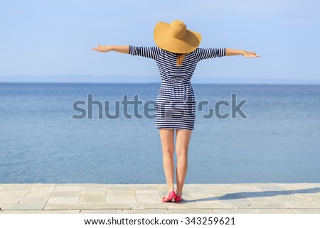 Young girl with a straw hat on the beach facing the sea