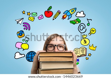 Young girl student with glasses leans on a pile of books and looks up with a pensive face on a blue background with icons. Concept of dreams and achievement of goals.