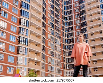 young girl student in glasses on the background of a skyscraper in a residential complex