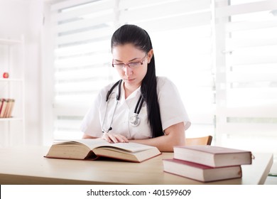 Young girl, student of medicine studying and researching books at desk in the office