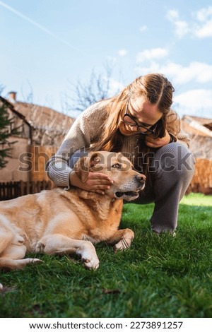 A young girl student is petting and feeding and playing with her pet dog labrador in backyard 