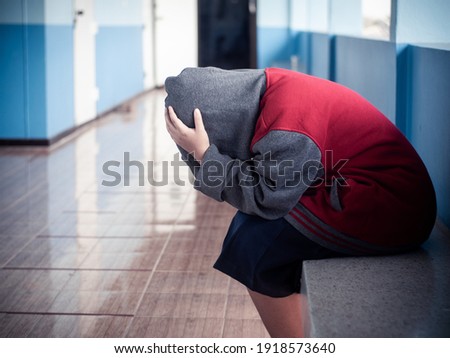 Young girl student sitting alone with sad feeling at school