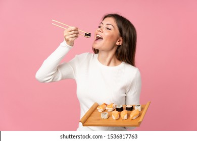 Young girl with sushi over isolated pink background