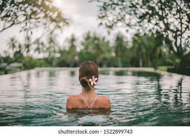 Young girl swimming in infinity pool with in private villa resort. Travelling to Ubud, Bali.