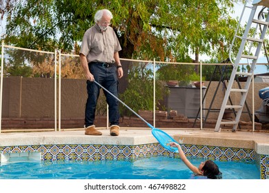 A young girl in a swimming pool places leaves one by one into a skimmer net that her grandfather is holding.  He holds it patiently as she helps him.  he is wearing slippers out by the pool. - Powered by Shutterstock