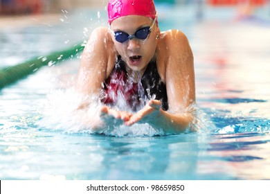 young girl swims breaststroke in the pool - Powered by Shutterstock