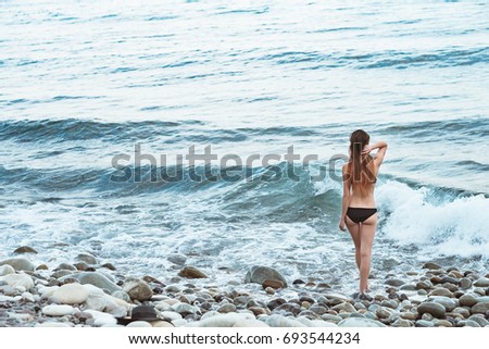 Young girl in swimsuit posing in sea with waves