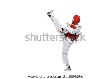Young girl, taekwondo practitioner strikes forcibly with the foot isolated over white background. Concept of sport, education, skills, workout, health. Sportsman wearing white dobok