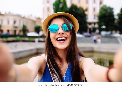 Young girl take selfie from hands with phone on summer city street. Urban life concept. - Shutterstock ID 450728395