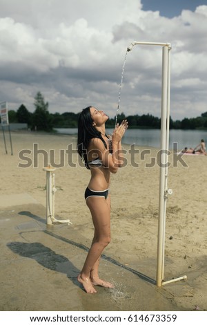 young girl takes a shower on the beach