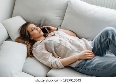 Young girl talking on the phone lying on the couch. High quality photo