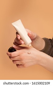 A Young Girl Testing, Applying  Foundation On Her Hand. Trying, The Tone, Nuance Of The Powder By Putting It On Her Arm. Selecting Make-up