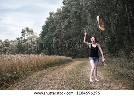 young girl throwing shoes, walking barefoot on dirt road through field and forest, summer and travel concept