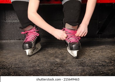 A Young Girl Ties Her Ice Hockey Skates in the Change Room of the Rink - Powered by Shutterstock