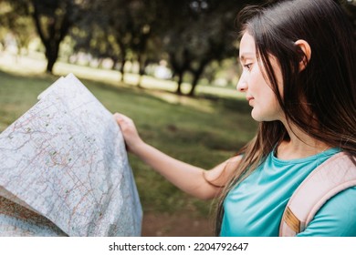 Young Girl Tourist, Wearing Turquoise T Shirt And A Pink Backpack, Checking The Map During Trek In The Park