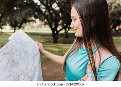 Young Girl Tourist, Wearing Turquoise T Shirt And A Pink Backpack, Checking The Map During Trek In The Park