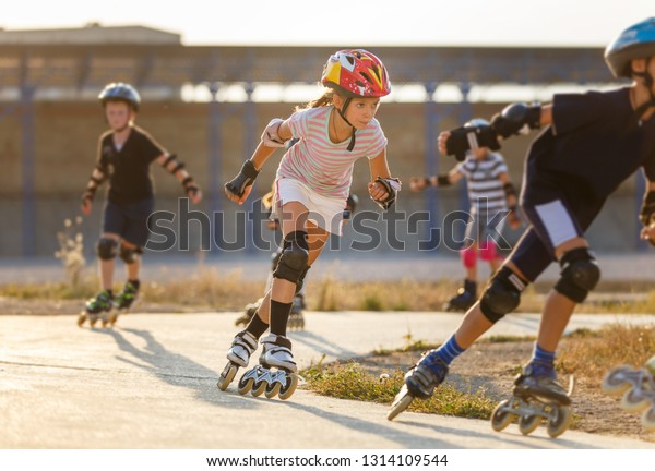 Young girl training inline skating with other\
children on rollerdrome