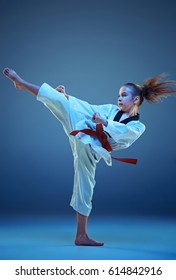 Young girl training karate on blue background