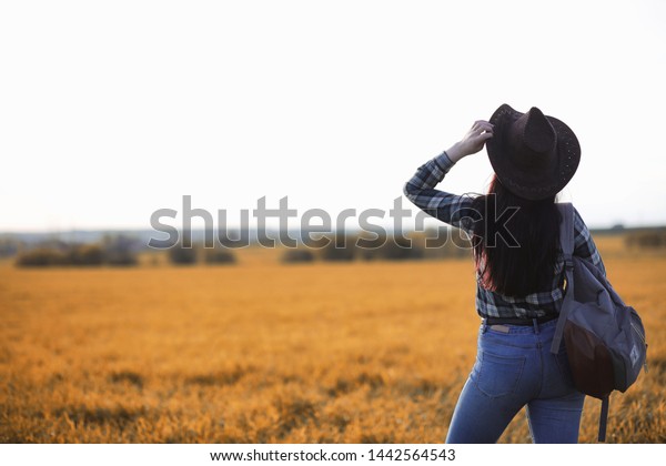 A young girl is traveling around the city\
hitchhiking. A beautiful young girl went on vacation. A female\
student in a cowboy hat on the\
road.\
