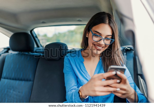 Young girl uses a mobile\
phone in the car. Technology cell phone isolation. Internet and\
social media. Woman with smartphone in her car. Girl is using a\
smartphone
