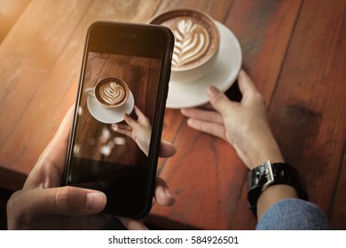 Young girl using Photography of smartphone of latte art coffee on mobile camera display while shooting. - Powered by Shutterstock