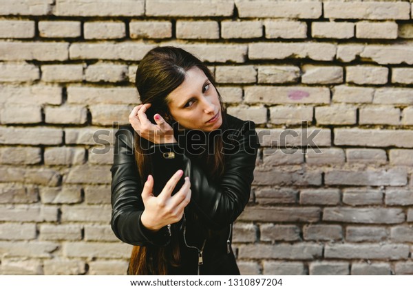 Young girl using the screen of\
her mobile phone as a mirror to put on makeup and remove pimples\
from her face, and she gets pretty for a date with her\
boyfriend.