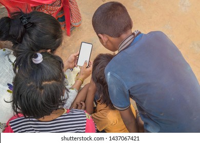 Young Girl With Village Girls And Boys Looking At Mobile Phone. Village Kids Education Concept.