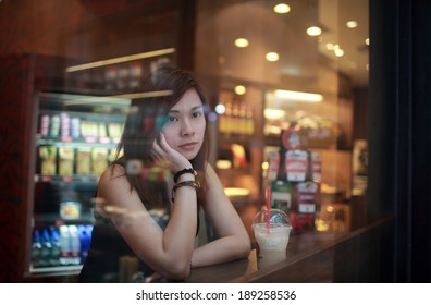 Young Girl waiting someone who late , hand on chin  , and looking out behind the cafe window , moment of enjoy her tea time deep thinking in hong kong - Shutterstock ID 189258536