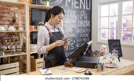 young girl waitress in apron standing in counter holding lots of money from cash box doing accounting after a day end. - Powered by Shutterstock