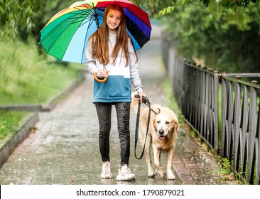 Young girl walking under rain with dog