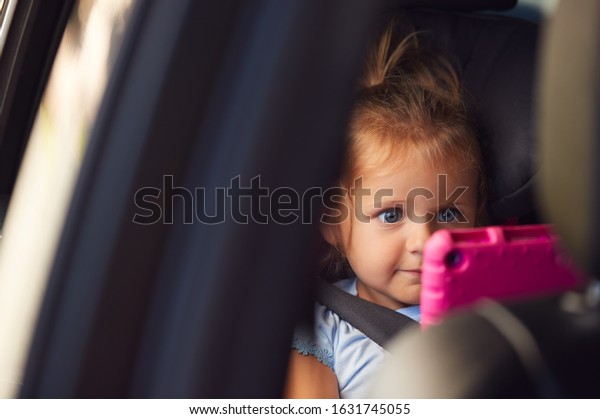 Young Girl Watching Digital Tablet In Back Seat\
On Car Journey