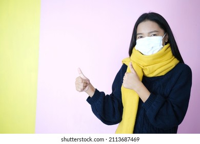 Young girl wear mask and sweater on pinkbackground.