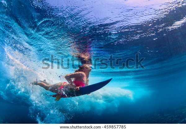 ビキニを着た若い女の子 波の下で水中に潜るサーフボードを持つサーファー 家族生活 水遊びのアドベンチャーキャンプ 子どもとの夏休みでのビーチエクストリーム水泳 の写真素材 今すぐ編集