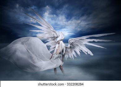 young girl wearing a costume, large white mask, big white wings belt with feathers that holds great white drapery that rides up behind her, standing in the lake in landscape with dramatic sky and fog.