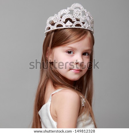Young girl wearing a crown and a white dress with a cute smile on Holiday