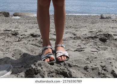 Young Girl Wearing Floral Print Sandals On A Sandy Beach On The Puget Sound.