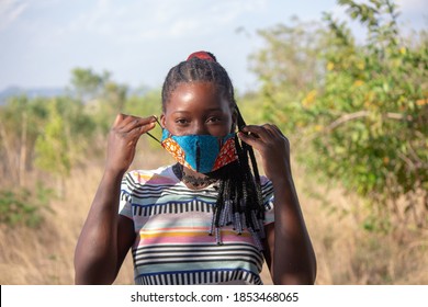 Young girl wearing a local handmade face mask using traditional African printed fabric sarong for protection against corona-virus - Powered by Shutterstock